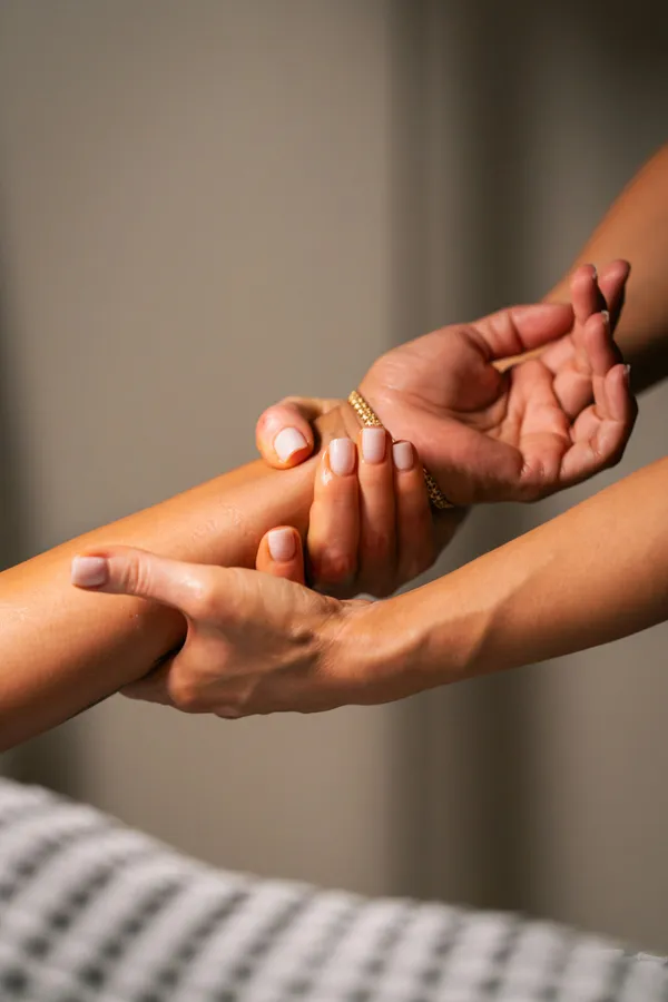 Mains massant l'avant-bras d'une cliente